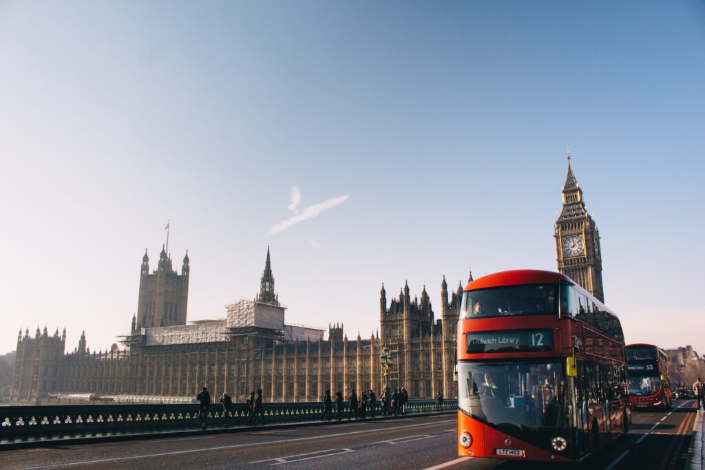 autobús rojo de dos pisos pasando por el Palacio de Westminster, Londres, durante el día